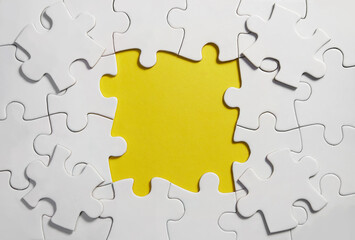 Unfinished white jigsaw puzzle pieces on yellow background