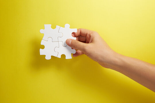 Hand holding puzzle pieces together in a conceptual image of teamwork and cooperation.