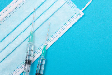 Several Syringe and Face Mask on Blue Table - Top View. Syringes are Prepared for Vaccination or Injection. Medical Experiment. Blue Disposable Medical Mask. Virus protection - Flat Lay