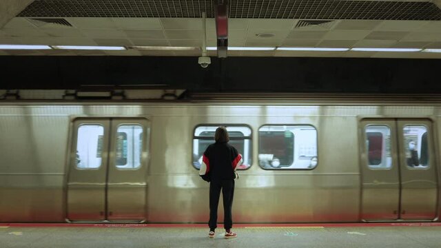 Back view of young woman waiting for subway train