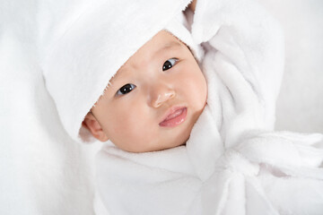 close up baby in soft bathrobe on bed