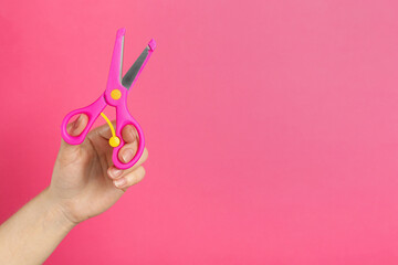 Woman holding small scissors on pink background, closeup. Space for text