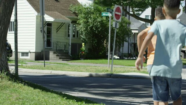 Two african american brothers running down neighbourhood sidewalk