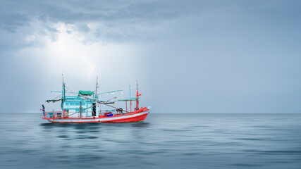 fishing boat floating in sea during strom coming with cloudy sky