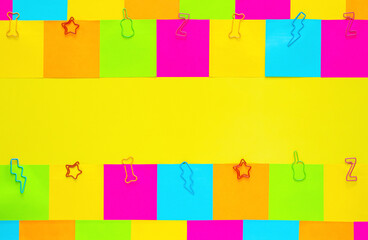 Colorful sticky note papers with paper clip on yellow background.