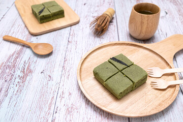 A serving of matcha green tea cannabis cake on a wooden plate.