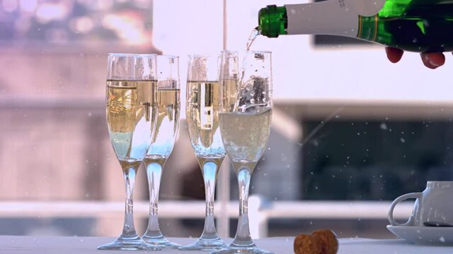 Animation of snow falling over champagne glasses on table