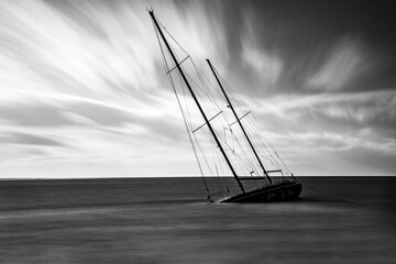 Sinking sailboat close to shore with beautiful wispy clouds in the background