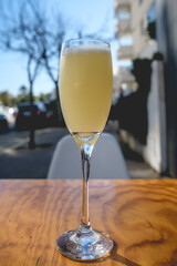 Glass of pisco sour (traditional peruvian liqueur with pisco, angostura bitters, egg and lemon) in a table in a sunny day