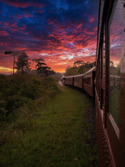 Trem Maria-Fumaça passando por Bento Gonçalves em céu dramático do por do sol.