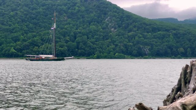 A sailboat going down the Hudson River at Little Stony Point in Cold Spring New York on a rainy summer day. 