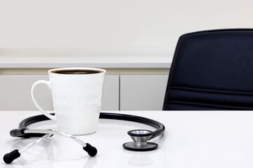 A doctor office with black stethoscope and black coffee on a table.