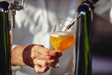 Shallow depth of field (selective focus) image with a man pouring craft beer from a dispenser into...