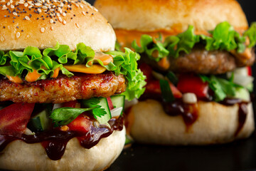 Extra Close-up of two Fresh tasty burgers with chicken, salad, cheesee and sauces. Fat unhealthy street food.