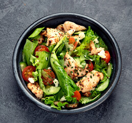 Fresh chicken salad on drak gray background. Healthy food concept.