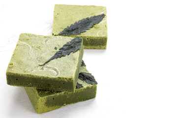 Bars of tasty matcha cannabis white chocolate cake on a white table.