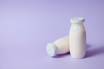 Bottles with probiotics and prebiotics dairy drink on light purple background. Bio yogurt with...