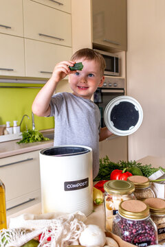 Child boy puts food waste in a compost bin. Waste sorting.
