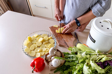 Boy child helps his mom to cook vegetable ratatouille standing in the kitchen. Family traditions.