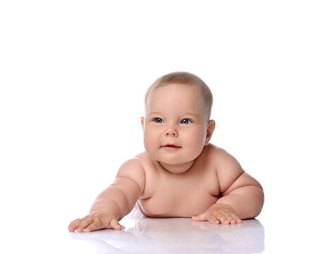 Healthy infant child baby girl kid in diaper is lying on her stomach holding arm outstretched, slapping on floor isolated on a white background