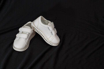 White shoes isolated on black background. Top view of fashionable trendy footwear.