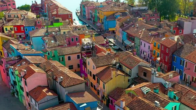 Horizontal panning aerial tour of bright multicolour colourful fishing houses in Burano Island Venice Italy. 