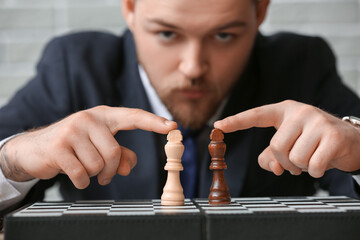Man with chess pieces on game board, closeup