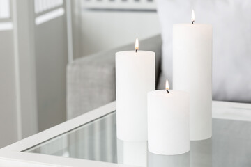 Burning candles on table in living room, closeup