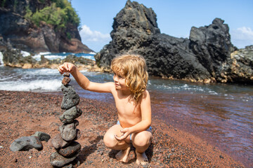 Child with zen stones on sea beach, meditation, spa and harmony. Calm balance concept. Kids play on the beach.