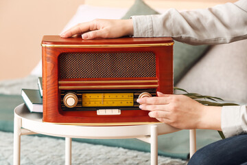 Woman with retro radio receiver on table in bedroom