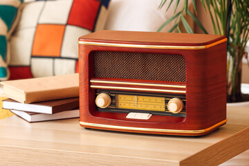 Retro radio receiver and books on table in bedroom, closeup