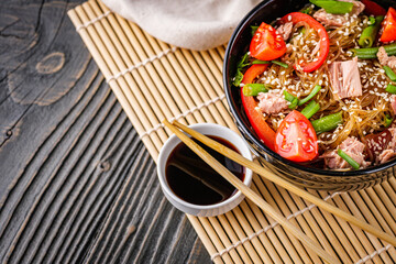 delicious glass noodles with tuna and vegetables on a dark wooden rustic background
