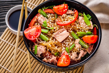 delicious glass noodles with tuna and vegetables on a dark wooden rustic background