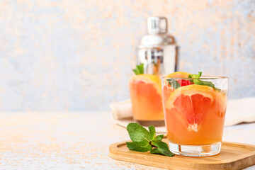 Glass of tasty grapefruit juice on light background