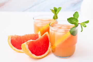 Glasses of tasty grapefruit juice on light background