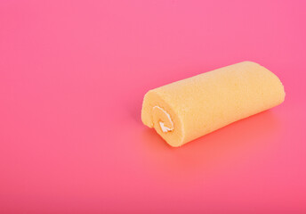 Orange cake roll with cream isolated on pink background.