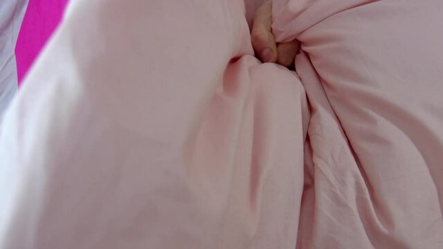A close-up on the hand of a young woman as she crushes and crumples a pillow, sheets in ecstasy The moment of orgasm while having sex.