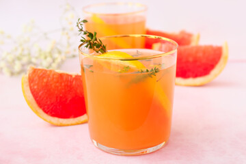 Glasses of tasty grapefruit juice on light background
