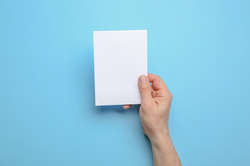 Man holding blank sheet of paper on color background, closeup