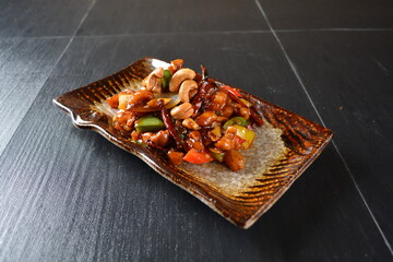 stir fried chicken meat with vegetable, cashew nut and dried chilli in sweet sauce on wood background asian halal menu