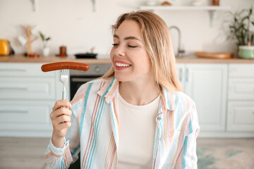 Young woman with tasty sausage in kitchen