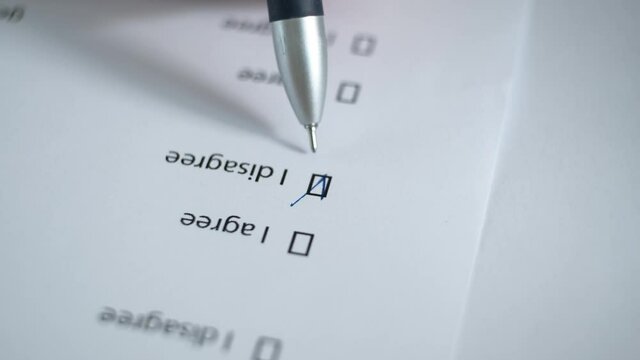 Filling out a paper document manually with the item "disagree". Blurred image.