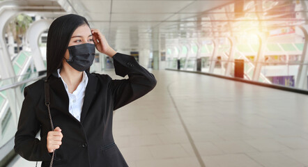 Young asian business woman in business black suit with protect mask for healthcare walking on street public outdoor and looking way. New normal and social distancing concept