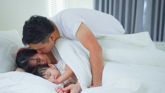 Asian loving hasband take care of wife and daughter in bedroom at home