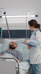 Practitioner woman doctor writing disease symptom on clipboard during rehabilitation appointment in hospital ward. Medical nurse putting oximeter on sick man patient monitoring heart pulse