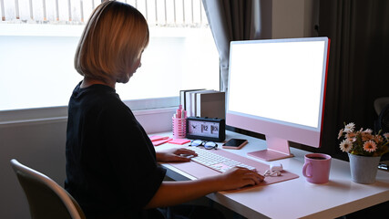 Side view female designer working with modern gadget at home office.