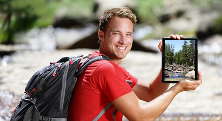 Tablet computer man hiker hiking in Yosemite, USA using travel app during hike showing screen of...