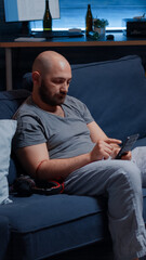 Traumatised, frustrated, stressed, depressed man listening music using headphones, sitting alone feeling emotionally unstable, lonely desperate, vulnerable suffering from anxiety, chronic disease
