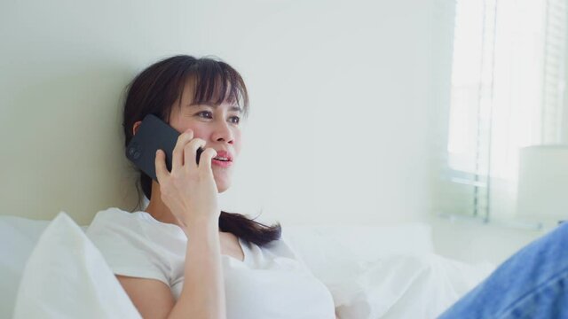 Asian attractive woman use mobile phone call on bed at home in morning