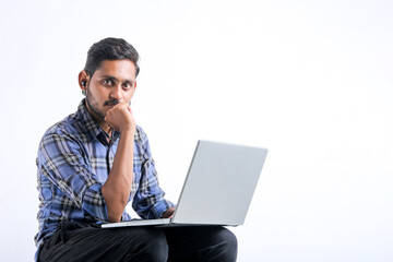 Young indian man using laptop over white background.
